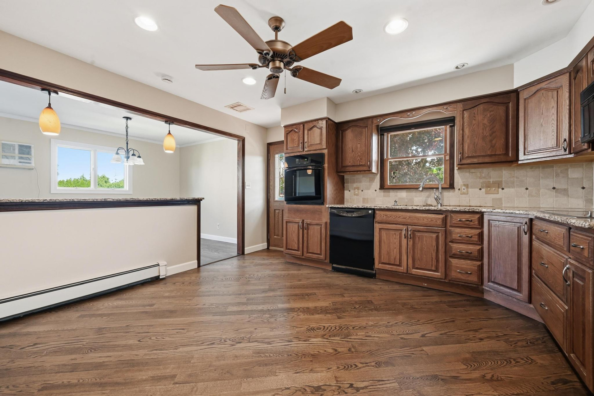 The same kitchen after the work, emptied with refinished hardwood floors, neutral walls and updated counters