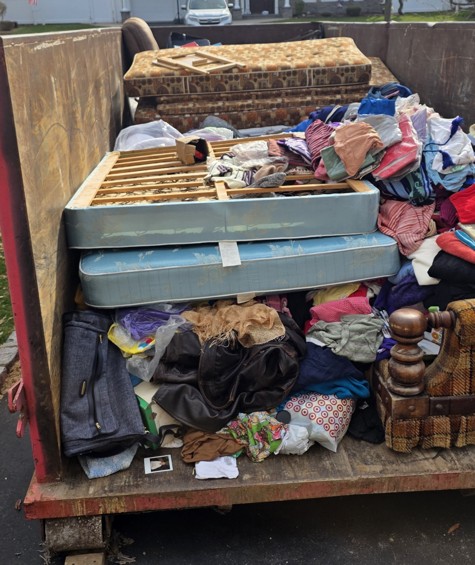 A dumpster filled with mattresses, clothing and furniture cleared from the home